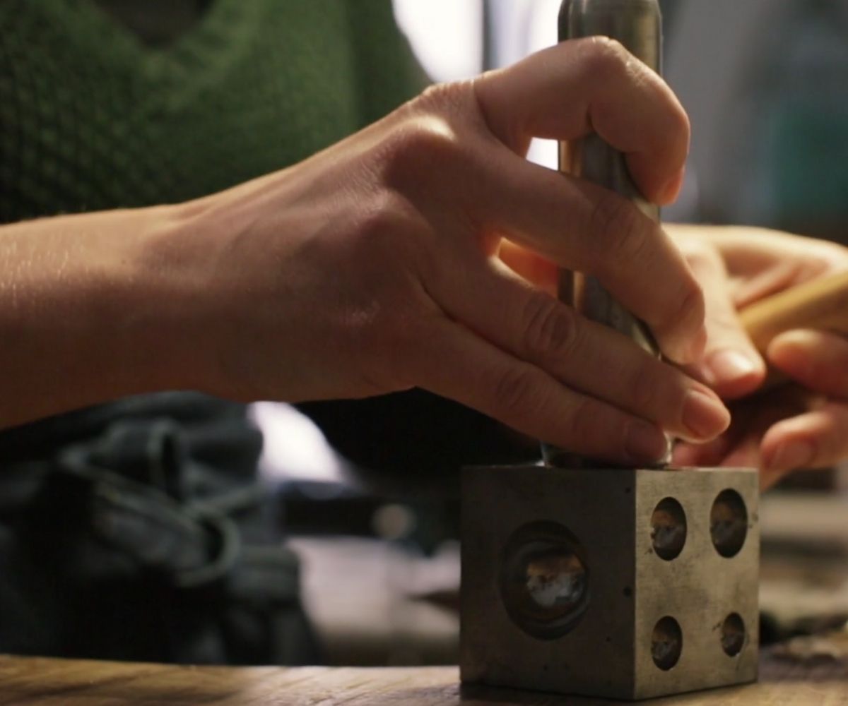 Denisa Piatti is hammering the metal into a mold to give her pieces their unique three-dimensional shape.